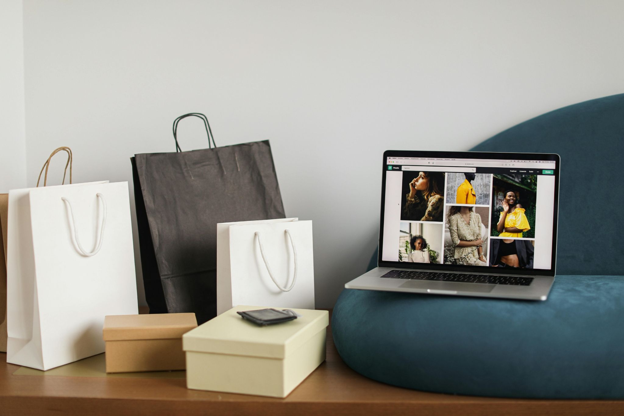 Picture of a laptop displaying a fashion website sitting next to paper shopping bags and boxes