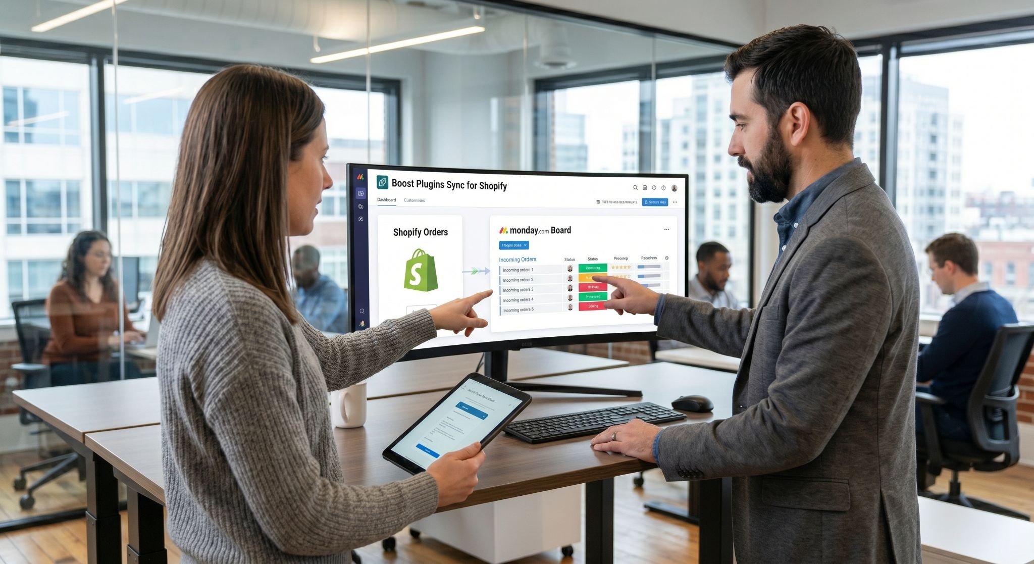 Picture of a man and a woman reviewing incoming orders synced to a Monday board on a large screen