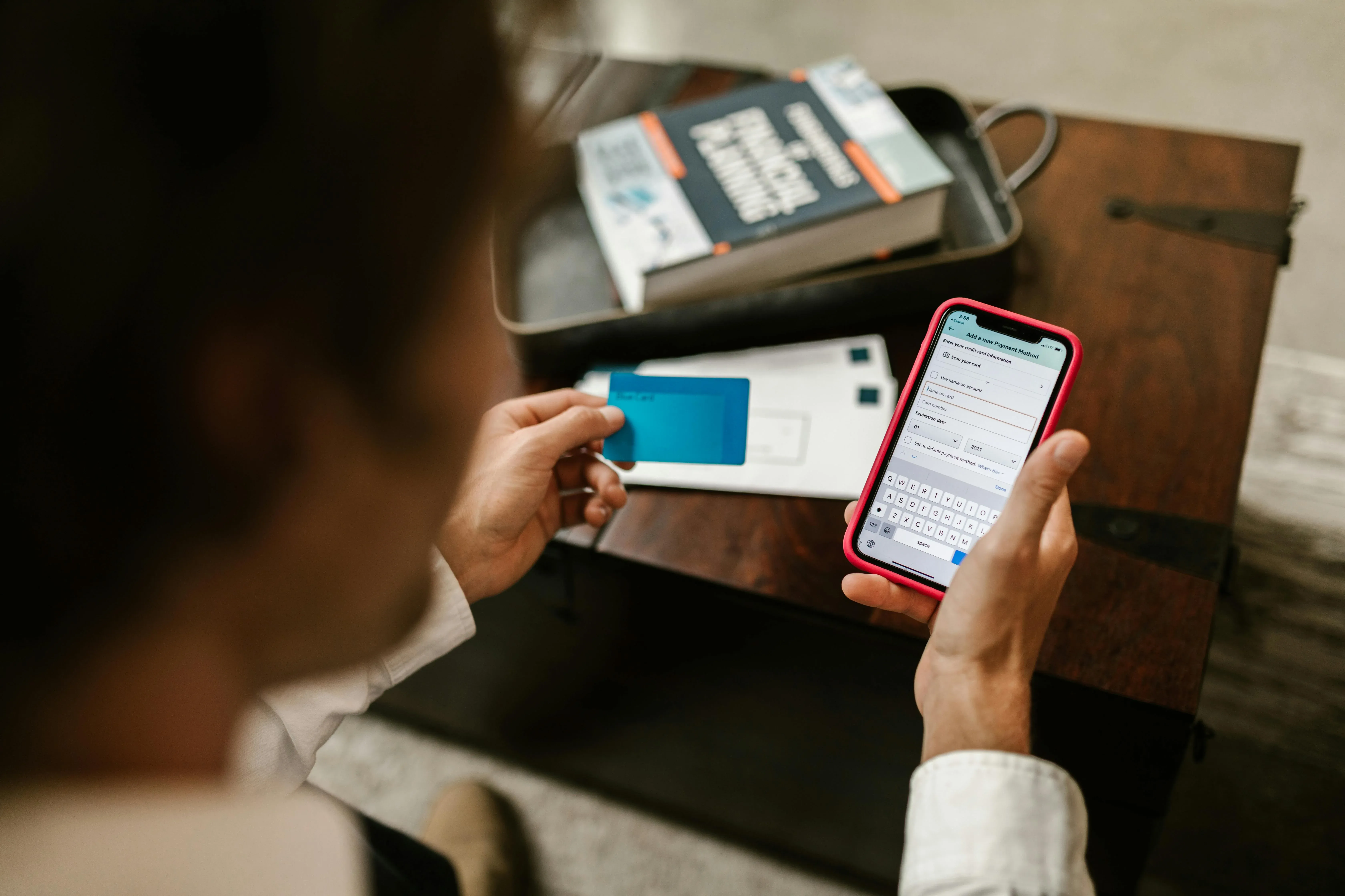 picture of a person holding a blue credit card while entering payment details on a smartphone
