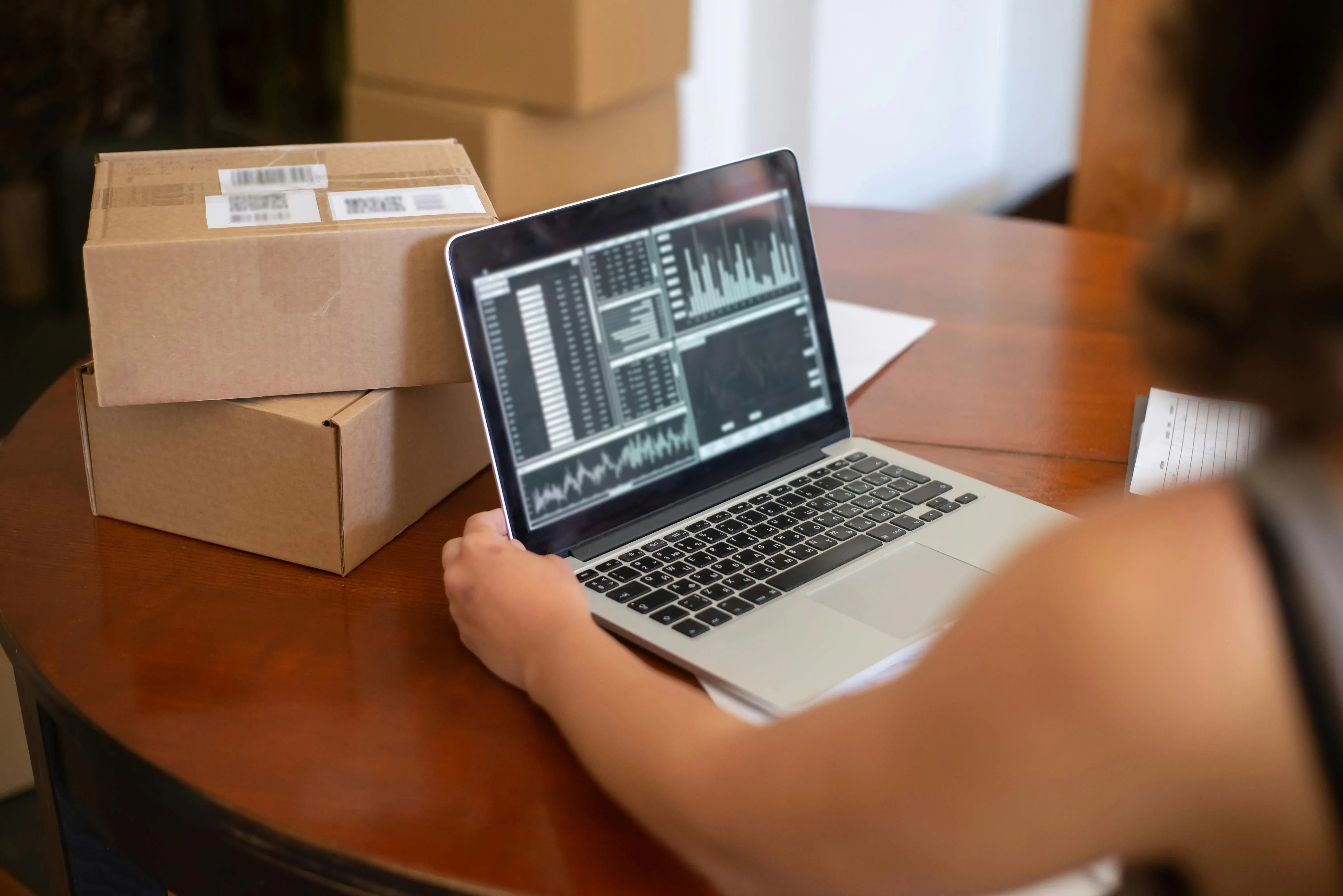 picture of a person looking at financial charts on a laptop next to two cardboard boxes
