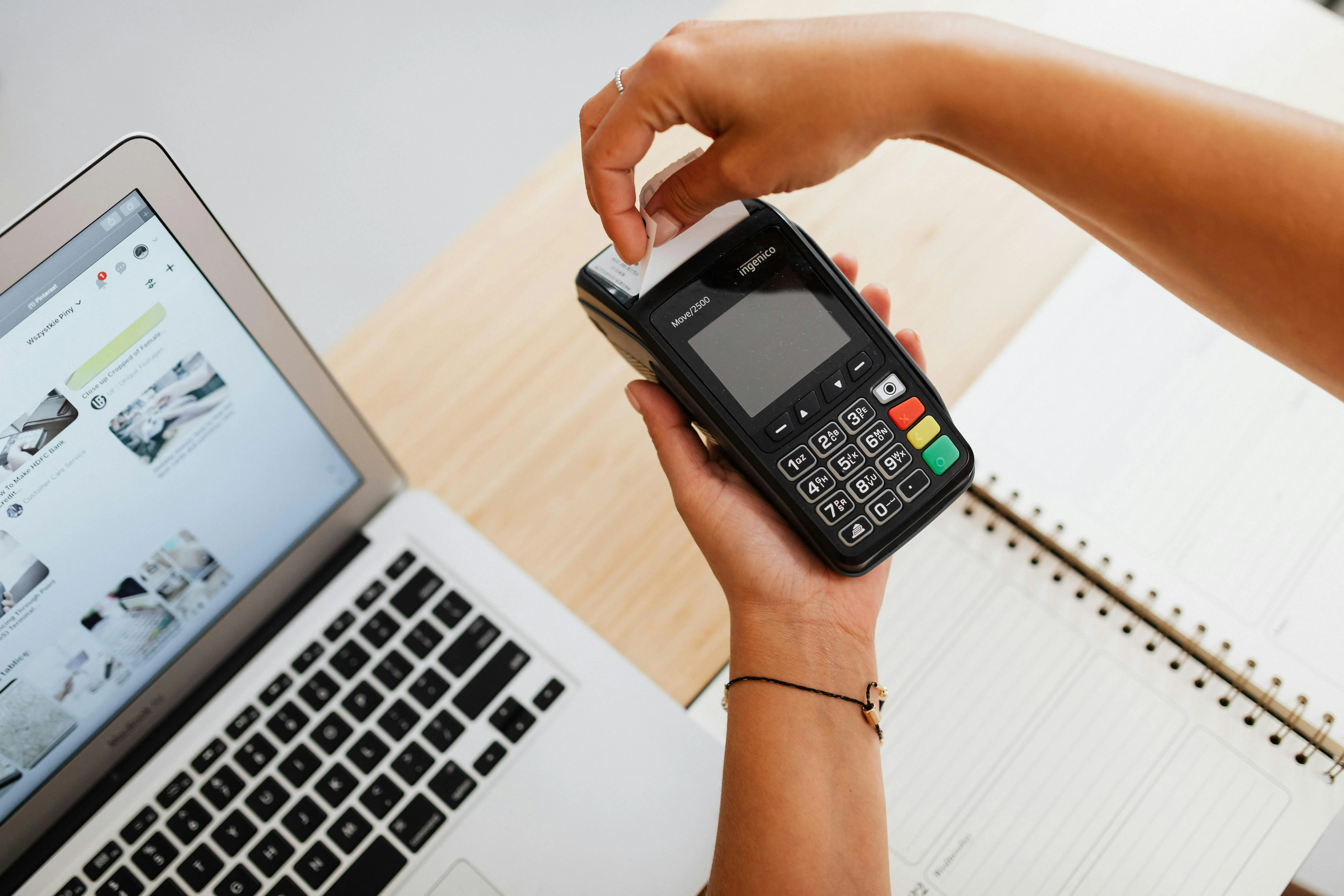 picture of a person pulling a printed receipt from a black handheld card payment terminal