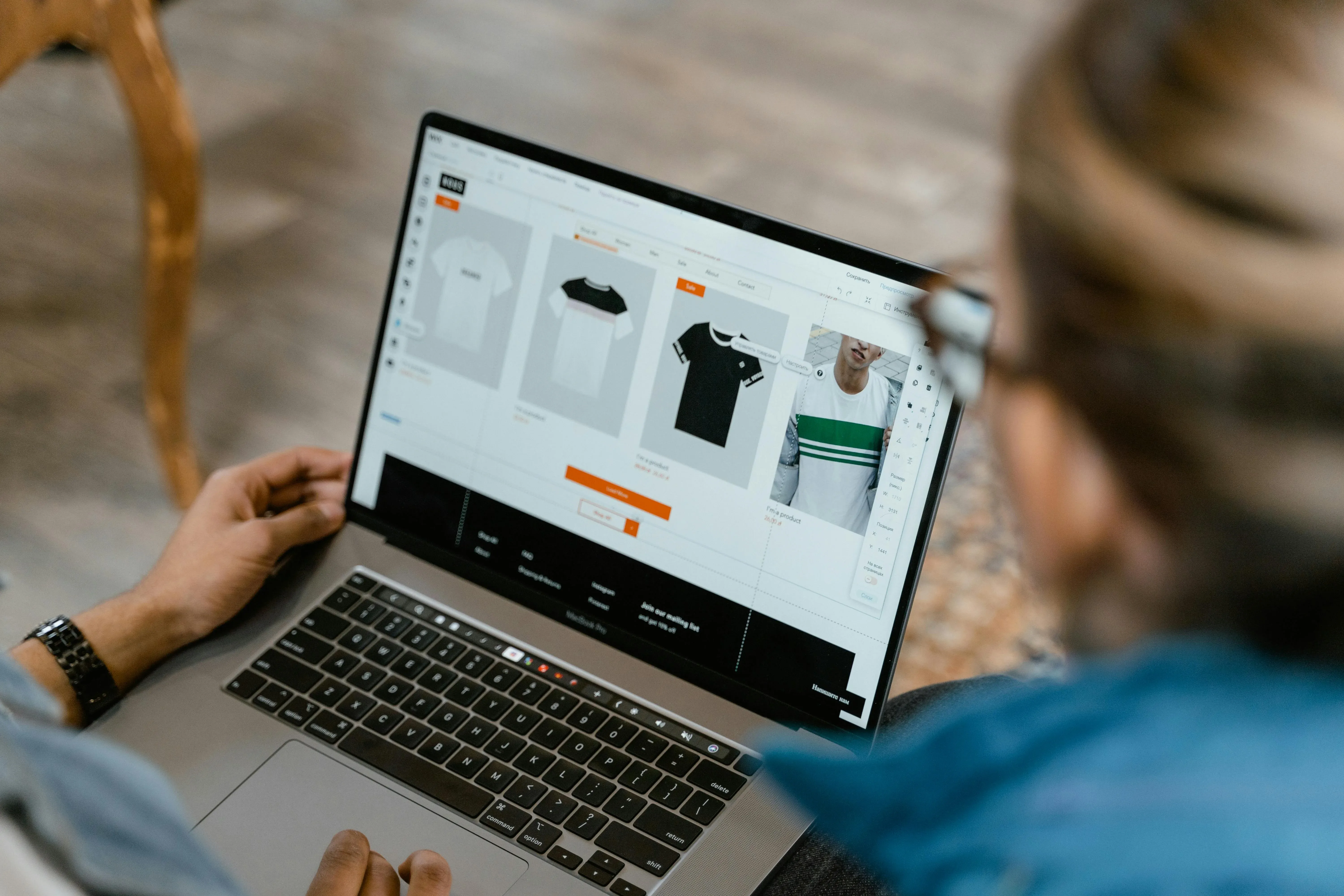 Picture of a person working on a laptop displaying an online clothing store interface