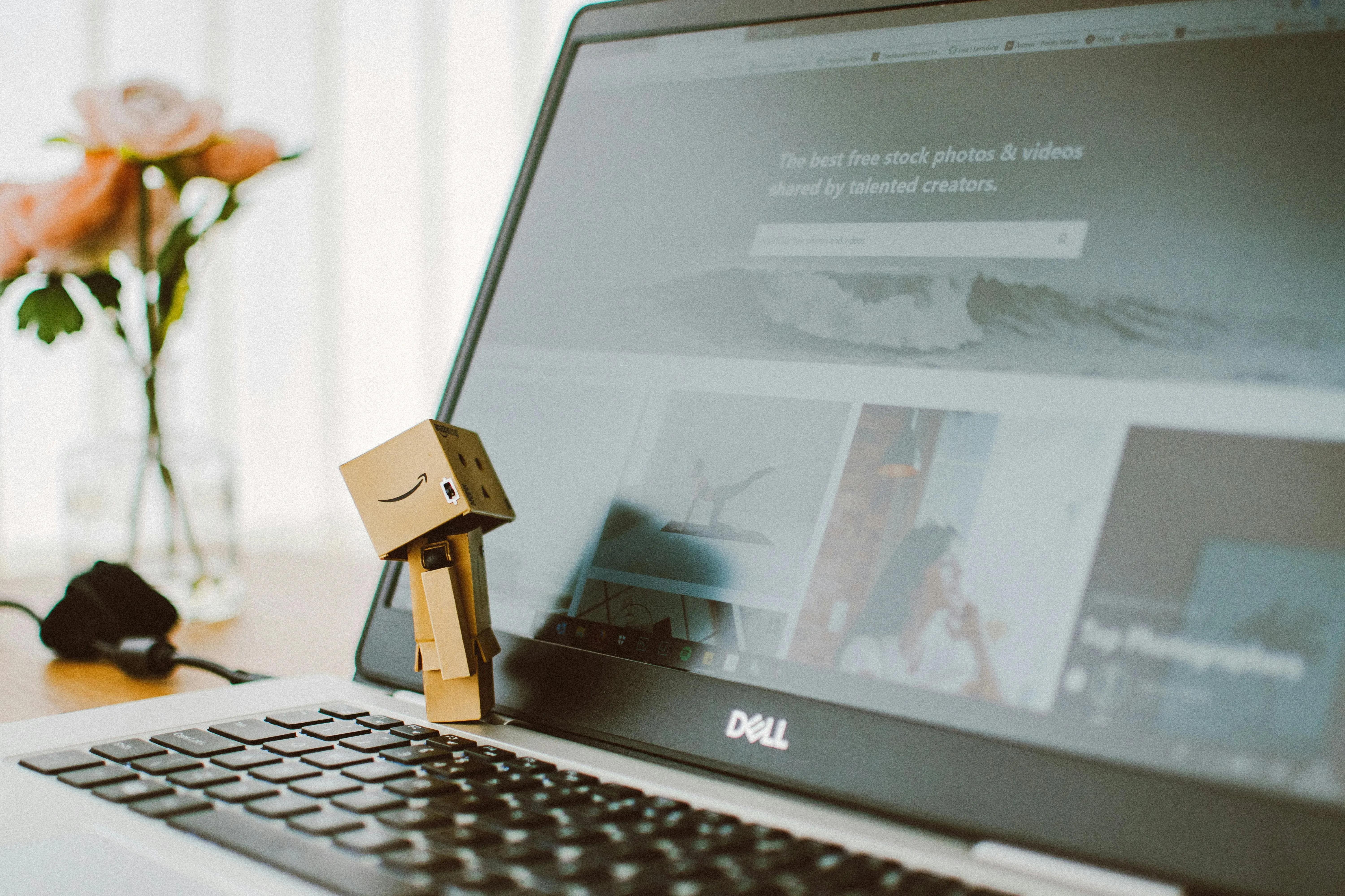 Picture of a small cardboard robot figurine standing on the keyboard of a laptop